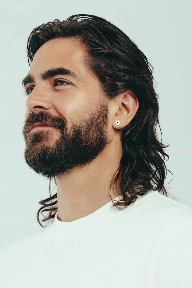 Confident caucasian man standing in a studio, with a look of self-assurance  on his face. Young man with perfect skin and facial hair embraces his  beauty and masculine appearance. stock photo