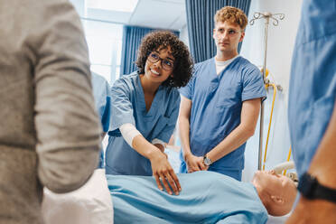 Eine Gruppe von Studenten in Kitteln bei der Ausbildung in einem klinischen Simulationszentrum. Junge Studenten des Gesundheitswesens lernen mit Patientensimulatoren in der Krankenpflegeschule. - JLPPF01759