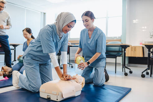 Zwei Medizinstudentinnen üben während einer klinischen Simulation die Herz-Lungen-Wiederbelebung mit Herzdruckmassage und Beatmung mit Beatmungsbeutel. Junge Frauen, die an der medizinischen Ausbildung in einem Lehrkrankenhaus teilnehmen. - JLPPF01774