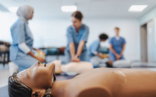 Medizinstudenten, die im Rahmen einer simulationsbasierten medizinischen Ausbildung die Herz-Lungen-Wiederbelebung erlernen. Unterschiedliche und junge Medizinstudenten üben die Herzdruckmassage an Übungspuppen in der medizinischen Ausbildung. - JLPPF01781