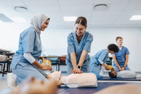 Zufriedene Medizinstudenten üben in einem Simulationszentrum für das Gesundheitswesen die Herz-Lungen-Wiederbelebung, einschließlich Herzdruckmassage und Beatmung mit Beatmungsbeutel. Studentinnen in der klinischen Ausbildung an der medizinischen Fakultät. - JLPPF01782