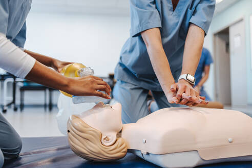 Medizinstudenten üben an einer Simulationspuppe die Herzdruckmassage und die Beatmung mit Beatmungsbeutel. Studentinnen in Kitteln lernen in der medizinischen Fakultät die Herz-Lungen-Wiederbelebung. - JLPPF01783