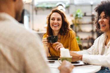Eine Gruppe junger Leute trifft sich zum Kaffee in einem gemütlichen Café, plaudert und informiert sich über das Leben der anderen. Drei glückliche Freunde, die am Wochenende zusammen abhängen. - JLPSF30088