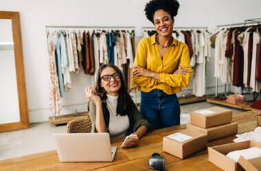 Porträt von zwei Frauen, die in die Kamera lächeln und Stolz und Zuversicht auf ihr erfolgreiches Online-Geschäft ausdrücken. Unternehmerinnen, die in einem Dropshipping- und E-Commerce-Kleinunternehmen zusammenarbeiten. - JLPSF30202