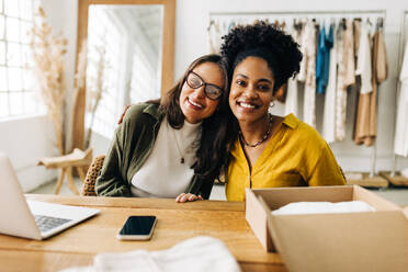 Geschäftsfrauen, die in einem Bekleidungsgeschäft zusammenarbeiten und ihre unternehmerischen Fähigkeiten kombinieren, um ihr Geschäft auf einer E-Commerce-Website zu eröffnen. Zwei Frauen, die ein erfolgreiches kleines Einzelhandelsunternehmen führen. - JLPSF30204