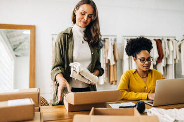 Dropshipping-Profis, die in einer Bekleidungsboutique Bestellungen für ihren Online-Shop abwickeln. Zwei unterschiedliche Frauen, die ihre Fähigkeiten als Einzelhändlerinnen und Unternehmerinnen zusammenbringen, um ein kleines Unternehmen zu führen. - JLPSF30208