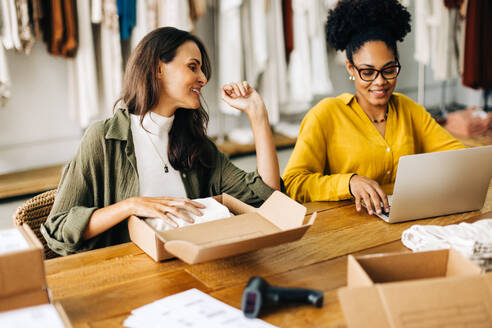 Female shop owners preparing to drop ship some clothing orders as they launch their online store. Two creative business women running a successful small business in the retail industry. - JLPSF30212