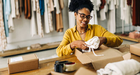 Erfolgreiche Geschäftsfrau, die in ihrem Bekleidungsgeschäft arbeitet und ein Paket für Dropshipping vorbereitet. Eine Frau, die bereit ist, ihr Online-Geschäft zu starten und eine zuverlässige E-Commerce-Unternehmerin zu werden. - JLPSF30223