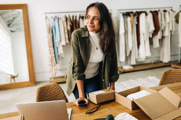 Von Erfolg und Leidenschaft getrieben, bereitet diese Geschäftsfrau eine Versandbestellung in ihrer Bekleidungsboutique vor, fest entschlossen, ihren Online-Shop zu eröffnen und eine erfolgreiche E-Commerce-Unternehmerin zu werden. - JLPSF30231