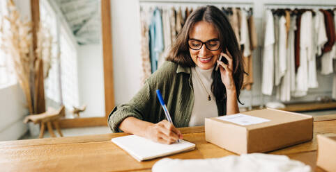 In ihrem erfolgreichen Online-Shop bestätigt die E-Commerce-Unternehmerin einen Versandauftrag mit einem Telefonanruf und stellt so sicher, dass jedes Paket schnell und präzise an ihre Kunden ausgeliefert wird. - JLPSF30241