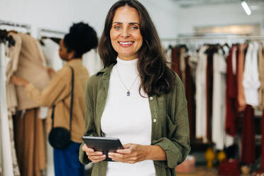 Portrait of a confident clothing store owner holding her digital tablet in her hands. Happy business woman running a successful small business, providing the best retail experience to her customers. - JLPSF30257