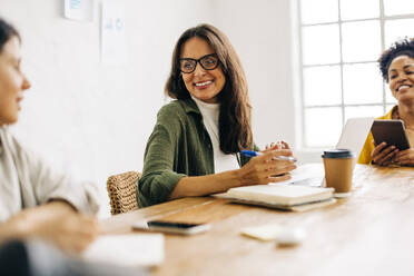 Group of diverse business women having a meeting in a boardroom, sharing ideas and collaborating for the success of their company. Happy female professionals working together on a project. - JLPSF30265