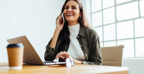 Geschäftsfrau, die in ihrem Büro erfolgreiche Geschäftsbeziehungen knüpft. Glückliche Unternehmerin, die ein produktives Telefongespräch mit ihren Mitarbeitern bei der Arbeit führt. - JLPSF30287