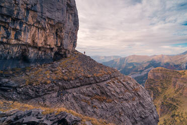 Blick auf einen fernen Reisenden, der auf einem felsigen Berghang in Ordesa y Monte Perdido steht - ADSF43924