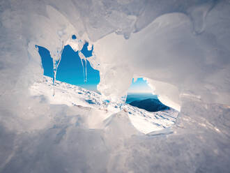 Malerische Landschaft mit Eishöhle und Eiszapfen vor blauem Himmel im Winter auf dem Berg Bola del Mundo - ADSF43928