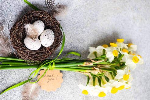 Von oben Osterkarte Konzept mit Nest mit Eiern und Narzissen Blumen im Bouquet - ADSF43989