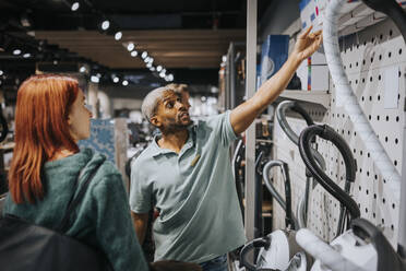 Salesman advising female customer in buying modern appliance at electronics store - MASF36680