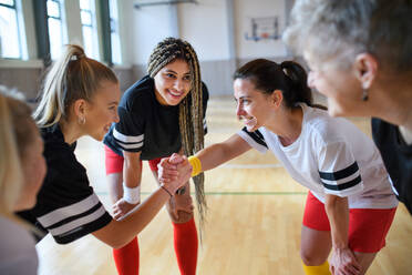 A group of young and old women in gym stacking hands together, sport team players. - HPIF09334