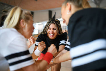 A group of young and old women in gym stacking hands together, sport team players. - HPIF09338