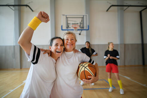 Eine Gruppe junger und älterer Frauen, Sportlerinnen, in der Turnhalle, die den Sieg feiern. - HPIF09378