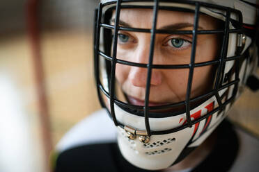Nahaufnahme einer Unihockeytorhüterin mit Helm, die sich auf ein Spiel in einer Turnhalle konzentriert. - HPIF09383