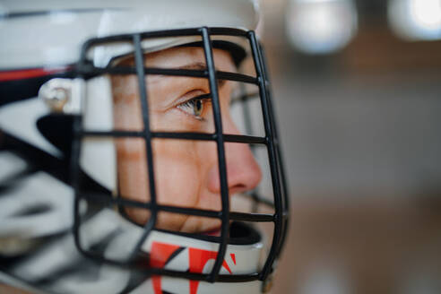 Nahaufnahme einer Unihockeytorhüterin mit Helm, die sich auf ein Spiel in einer Turnhalle konzentriert. - HPIF09384