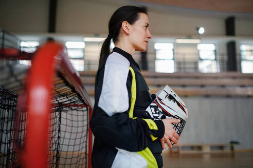 A close-up of woman floorball goalkeeper in helmet concetrating on game in gym. - HPIF09387