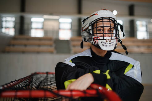 A close-up of woman floorball goalkeeper in helmet concetrating on game in gym. - HPIF09388