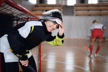 Nahaufnahme einer Unihockeytorhüterin mit Helm, die sich auf ein Spiel in einer Turnhalle konzentriert. - HPIF09389