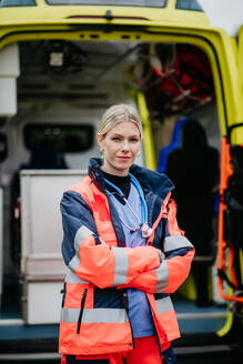 Portrait of a young woman doctor standing in front of ambulance car. - HPIF09419