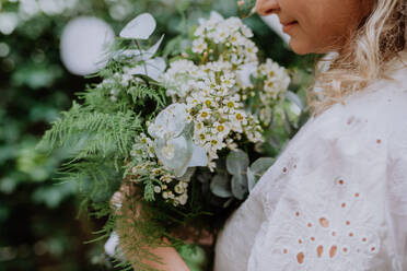 Nahaufnahme des Brautstraußes in den Händen der Braut beim Empfang draußen im Hinterhof - HPIF09478