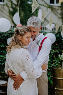 Nahaufnahme von Braut und Bräutigam beim Tanzen auf ihrer Hochzeit im Freien. - HPIF09495