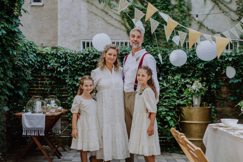 Reife Braut und Bräutigam posieren mit ihren Töchtern bei der Hochzeitsfeier draußen im Hinterhof. - HPIF09501