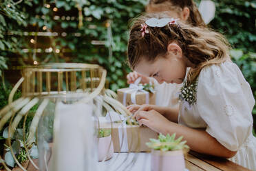 Kleine Mädchen bereiten ein Geschenk für die Braut auf einem Hochzeitsgartenfest vor. - HPIF09511