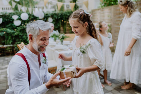 Ein reifer Vater Bräutigam erhalten Geschenk von seiner Tochter bei der Hochzeitsfeier draußen im Hinterhof. - HPIF09533