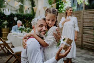 Ein reifer Vater Bräutigam erhalten Geschenk von seiner Tochter bei der Hochzeitsfeier draußen im Hinterhof. - HPIF09536