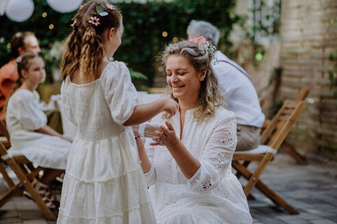 Kleines Mädchen gibt ein Hochzeitsgeschenk an reife Braut bei Hochzeit Hinterhof Party. - HPIF09538