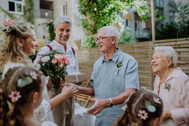 Eine reife Braut empfängt Glückwünsche beim Hochzeitsempfang draußen im Hinterhof. - HPIF09542