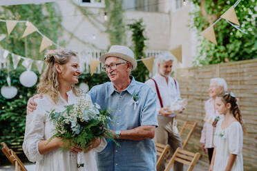 Reife Braut mit ihrem Vater bei der Hochzeitszeremonie im Garten. - HPIF09548