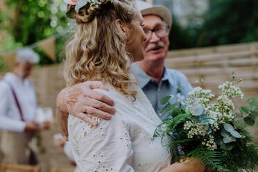 Eine reife Braut empfängt Glückwünsche beim Hochzeitsempfang draußen im Hinterhof. - HPIF09549