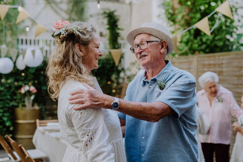 Eine reife Braut empfängt Glückwünsche beim Hochzeitsempfang draußen im Hinterhof. - HPIF09550