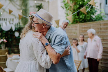 Eine reife Braut empfängt Glückwünsche beim Hochzeitsempfang draußen im Hinterhof. - HPIF09551