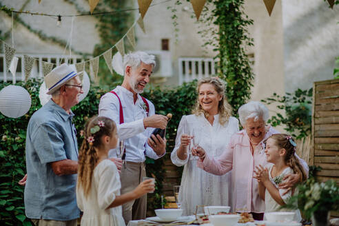 Eine reife Braut und ein reifer Bräutigam stoßen mit den Gästen auf der Hochzeitsfeier im Hinterhof an. - HPIF09552