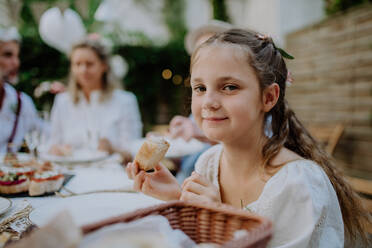 Hochzeitsgäste, die an einem Tisch sitzen und bei einem Empfang im Garten essen und trinken. - HPIF09561