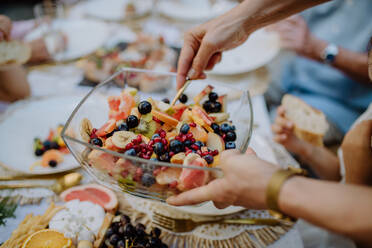 Hochzeitsgäste servieren Obstsalat bei einer Gartenparty im Freien. - HPIF09562