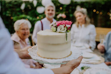 Eine reife Braut und ein reifer Bräutigam, die bei einer Hochzeitsfeier im Hinterhof eine Torte bekommen. - HPIF09567