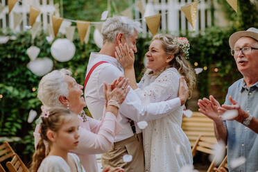 Ein reifes Brautpaar feiert seine Hochzeit im Kreise seiner Familie in einem Hinterhof. - HPIF09571