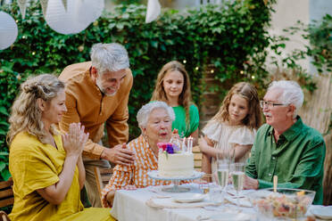 Eine Mehrgenerationen-Familie auf einem Sommergartenfest im Freien, die ihren Geburtstag feiert - HPIF09574