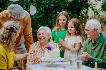 Eine Mehrgenerationen-Familie auf einem Sommergartenfest im Freien, die ihren Geburtstag feiert - HPIF09576
