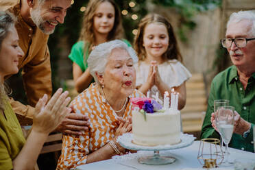 Eine Mehrgenerationen-Familie auf einem Sommergartenfest im Freien, die ihren Geburtstag feiert - HPIF09577